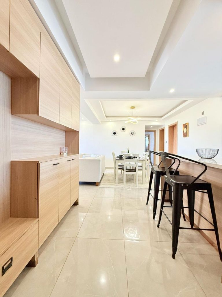 The dining area and the partial view of the couches and the kitchen at the Fully Furnished 3 bedroom Apartment in Westlands