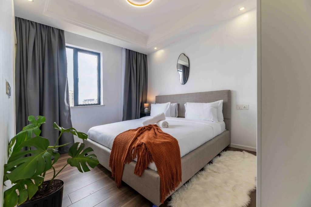 Bedroom with large windows partially covered by curtains at Family-friendly serviced apartment in Kilimani