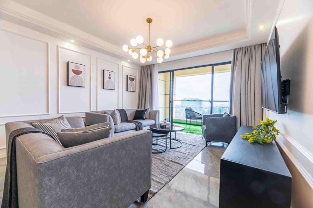 Family-friendly serviced apartment in Kilimani bright living room with couches nesting tables and a mounted smart Tv