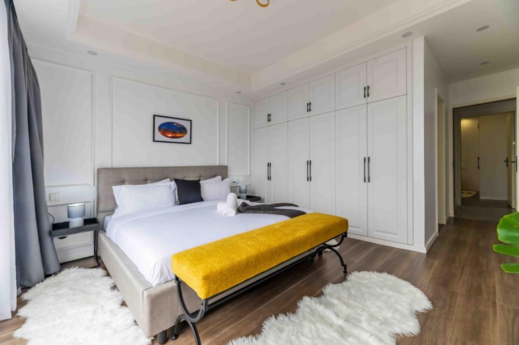 Expansive bedroom with king size bed a, white linens and view if the inbuilt wardrobes