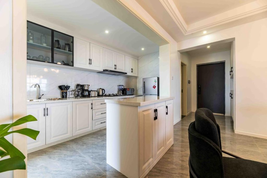Elegant open plan kitchen kitchen fitted with white cabinets and appliances at Family-friendly serviced apartment in Kilimani