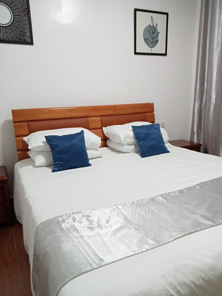 a classy queen size bed with white linen at Budget 2 bedroom furnished apartment Kilimani