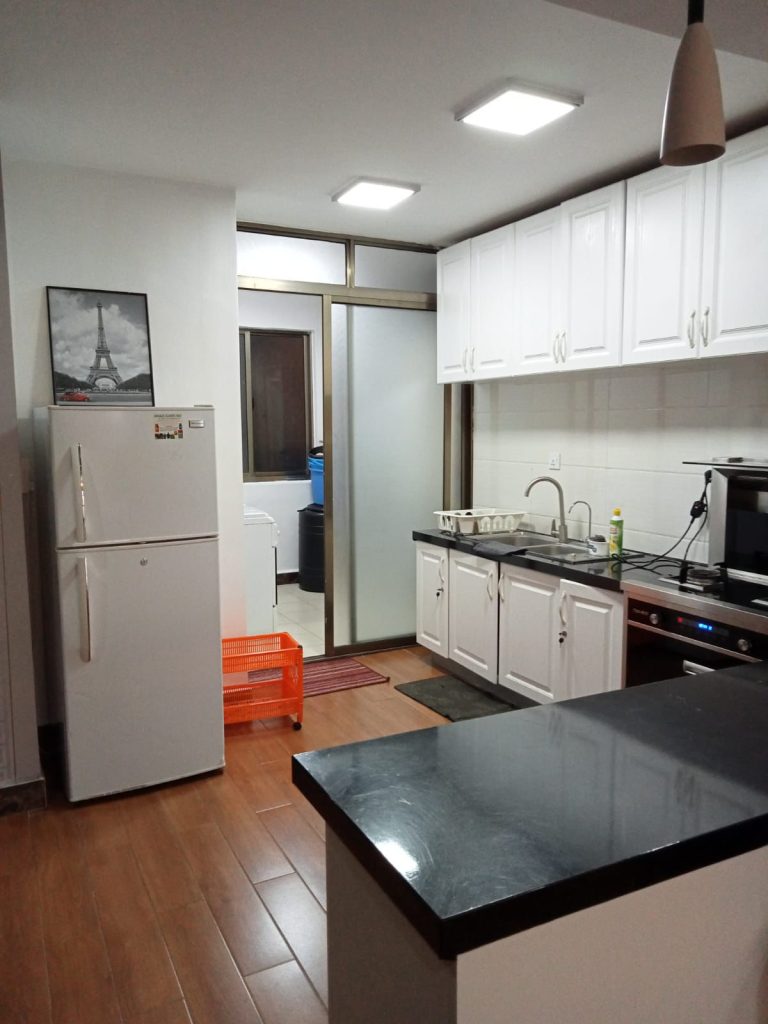 open kitchen fitted with white cabinets and appliances at the Budget 2 bedroom furnished apartment Kilimani