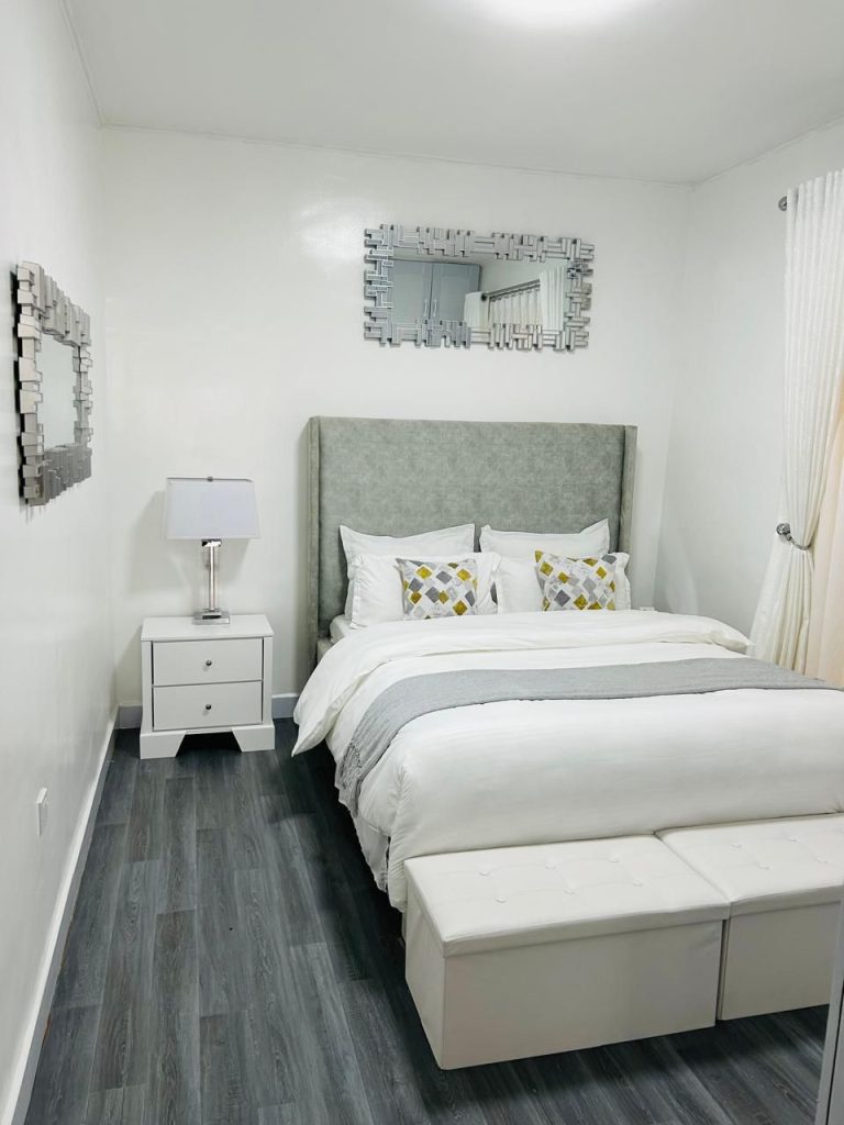 a king size bed with white linen and yellow throw pillows at Kilimani 2 bedroom Airbnb with swimming pool