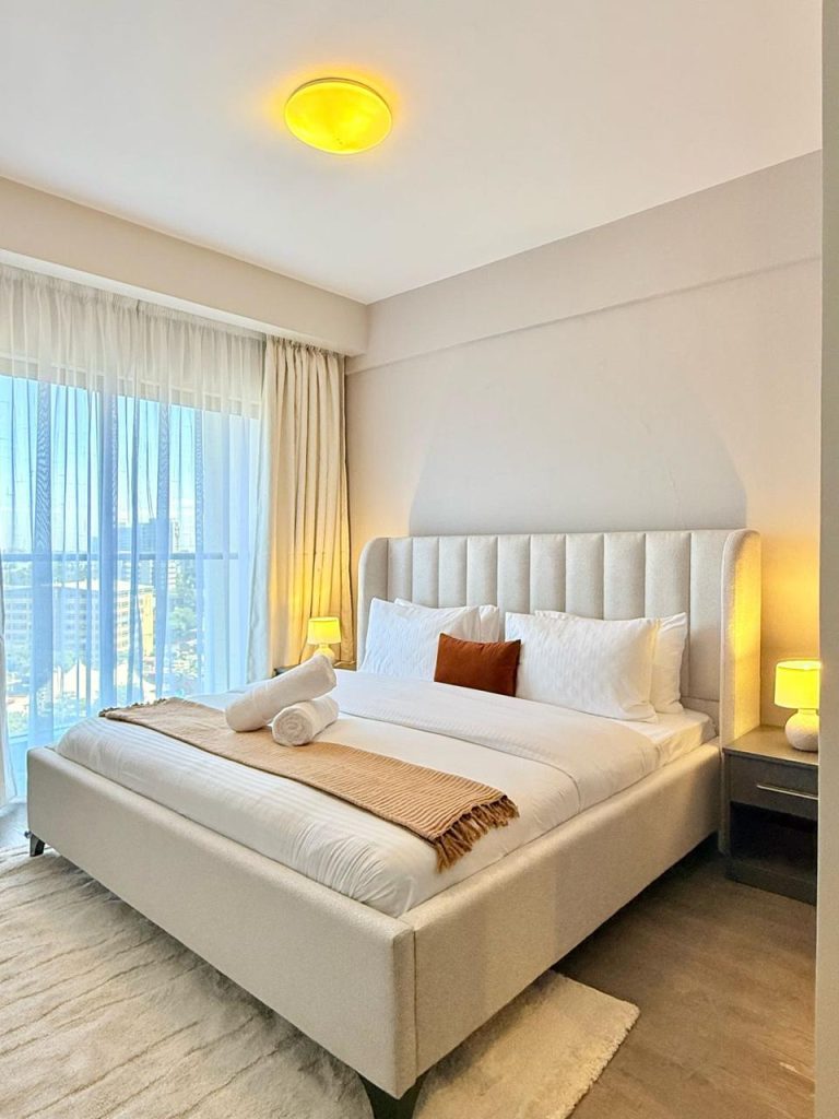 A queen size bed in a bedroom with large windows at Furnished Apartment for Digital Nomads in Nairobi
