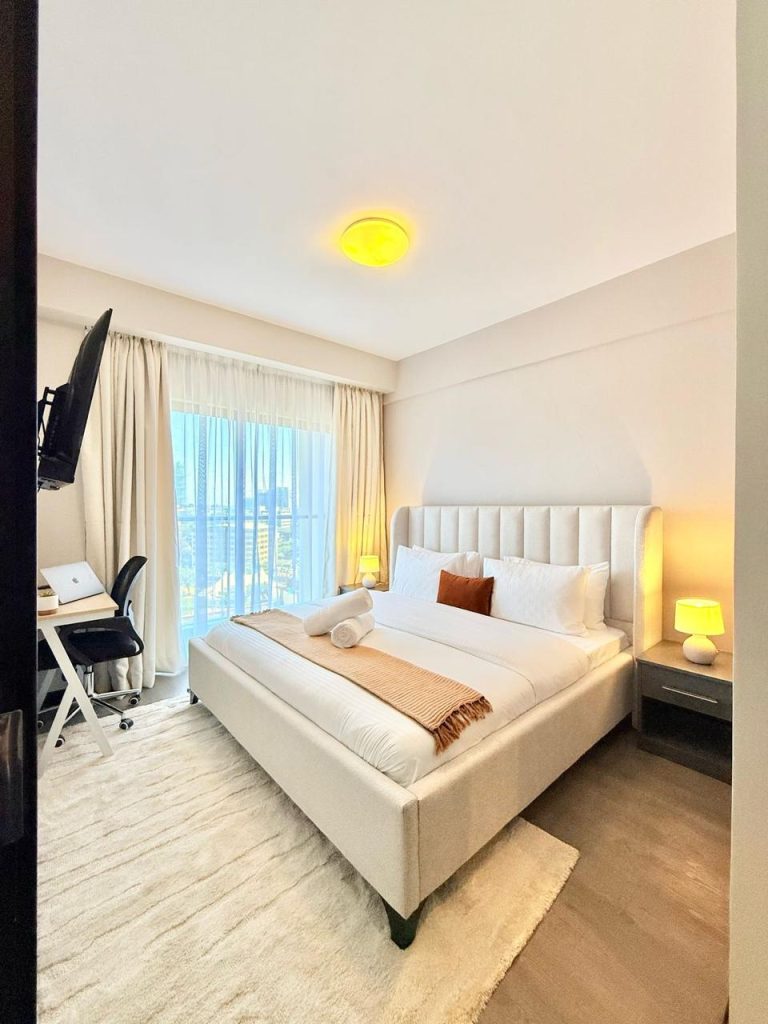 a queen sized bed, a mounted Tv, Study Desk and large windows in a bedroom at Furnished Apartment for Digital Nomads in Nairobi