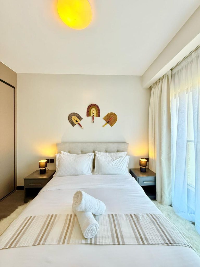 bedroom with a medium bed and partial view of inbuilt wardrobes and large windows at Furnished Apartment for Digital Nomads in Nairobi