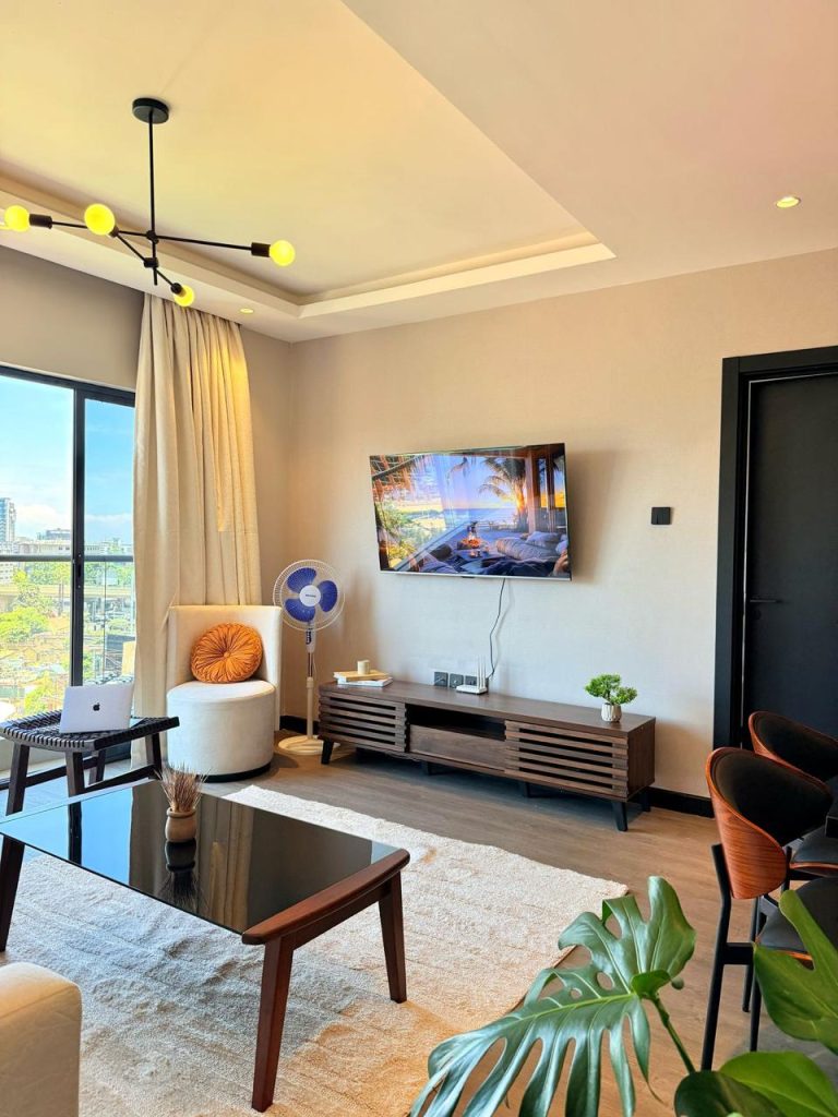 A smart Tv Mounted, A tv Console and an accent couch at Furnished Apartment for Digital Nomads in Nairobi