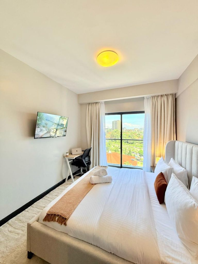 view of the study desk,large windows and a mounted smart Tv at Furnished Apartment for Digital Nomads in Nairobi
