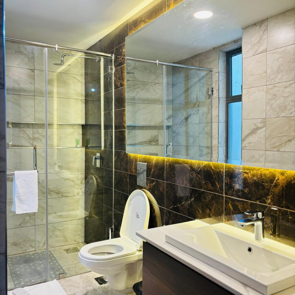 bathroom with cubicle glass shower,a toilet and a sink at the Furnished 3 bedroom Apartment in Gated Community