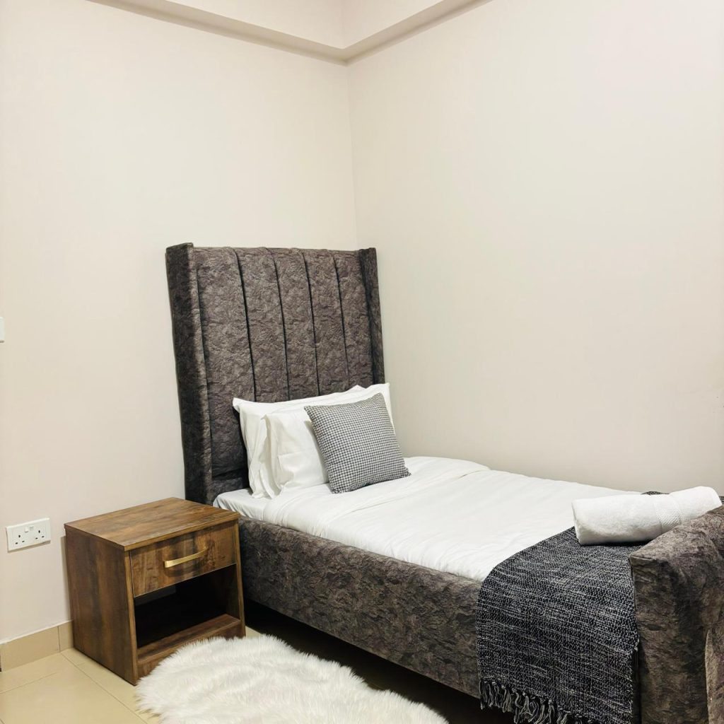 a bedroom with a medium size bed and a night stand table at the Furnished 3 bedroom Apartment in Gated Community