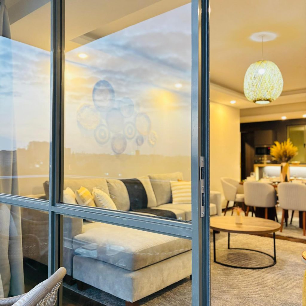 the view of a couch in the living room from the outside through sliding large widows at the Furnished 3 bedroom Apartment in Gated Community