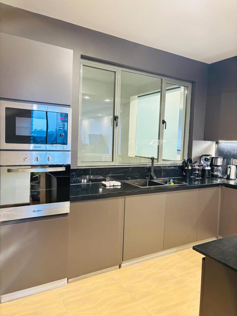 view of the kitchen sink ,cooker ,microwave, cutlery and ther provisions at the Furnished 3 bedroom Apartment in Gated Community