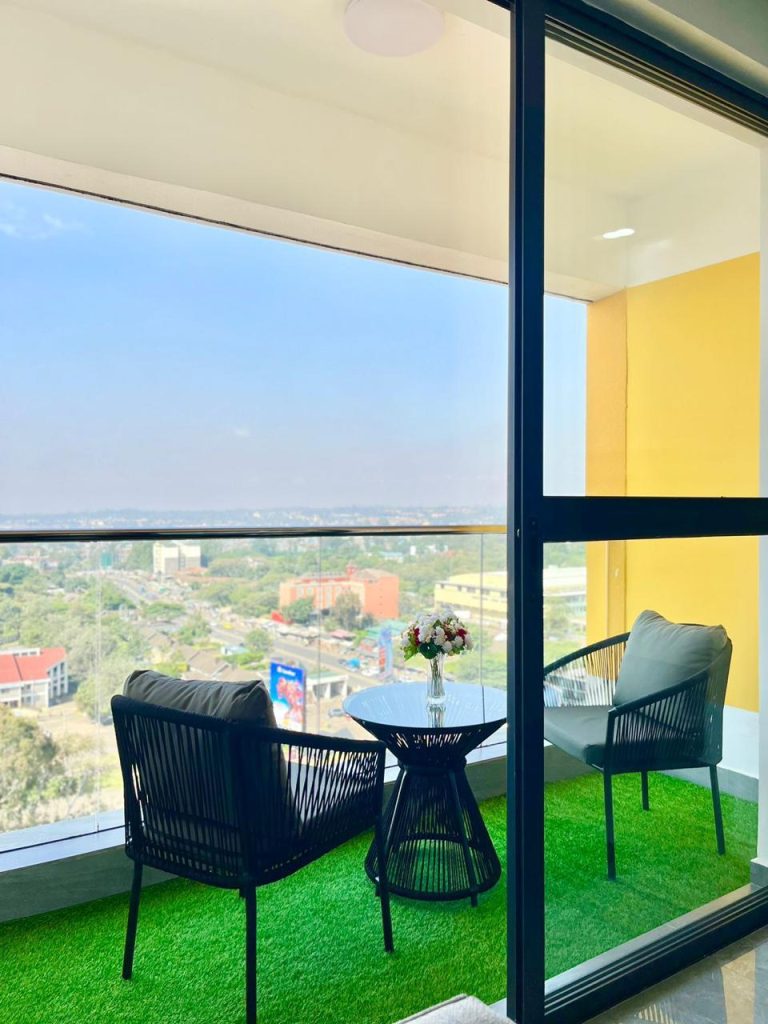 a balcony with 2 seats and a medium glass table at Two Bedroom Furnished Apartment for rent in Nairobi