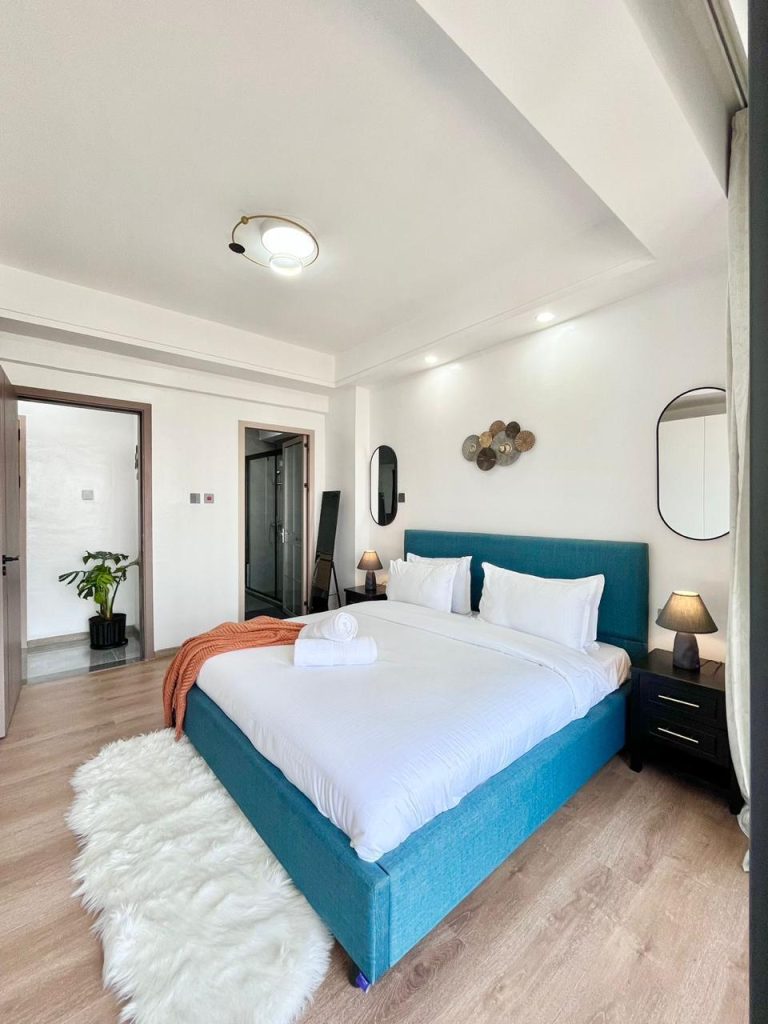 an ensuite bedroom with a king size bed ,white beddings and mirrors at the Two Bedroom Furnished Apartment for rent in Nairobi