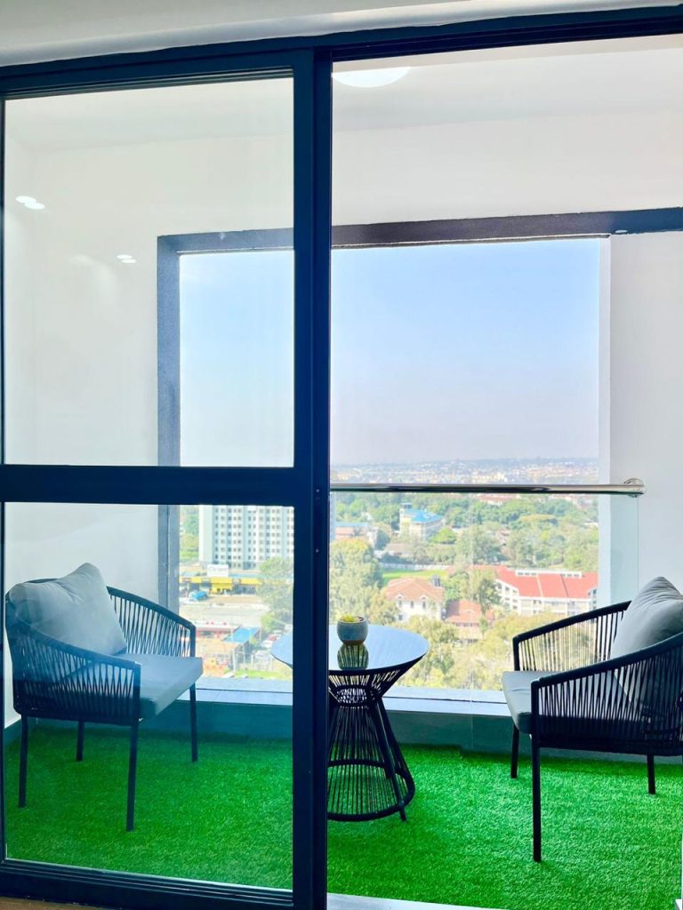 a balcony with 2 seats and a medium table at Two Bedroom Furnished Apartment for rent in Nairobi
