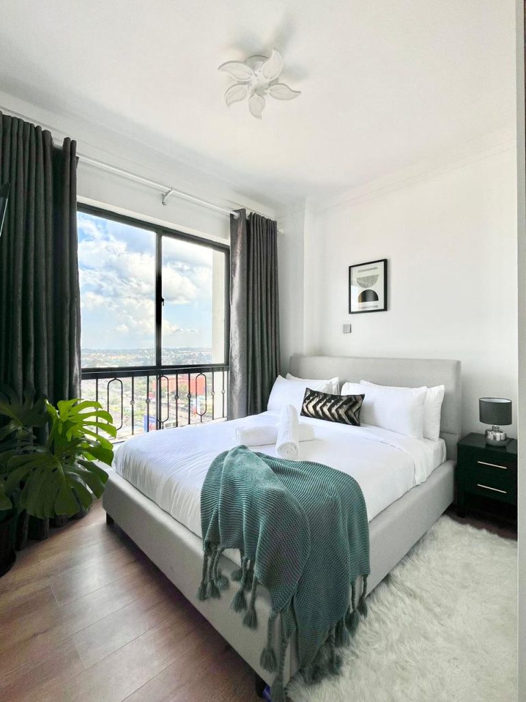 a beautiful queen size bed with white beddings and a green throw blanket at the Two Bedroom Furnished Apartment for rent in Nairobi