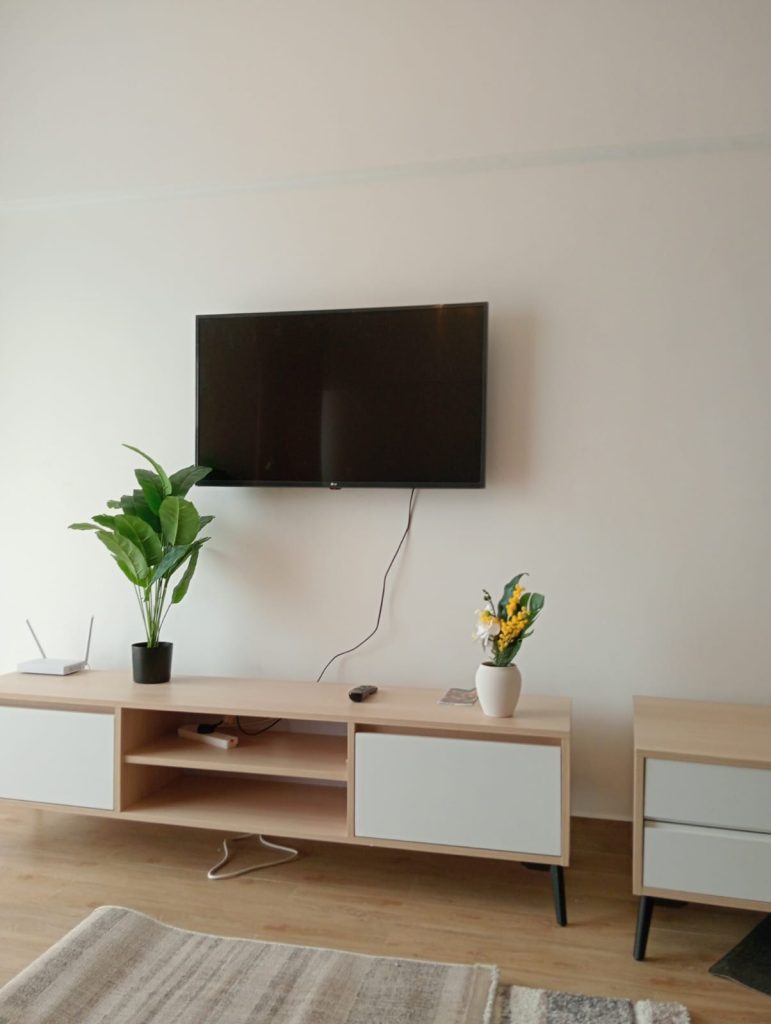 a mounted tv in the living room and a tv console under it at the Furnished 2-Bedroom Apartment for Daily Rentals in Kilimani