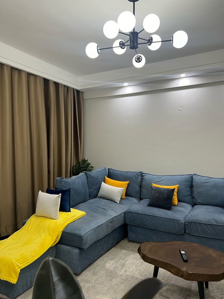 soft blue couch with white and yellow throw pillow at Furnished 2 bedroom Apartment Ideal for Extended Stay