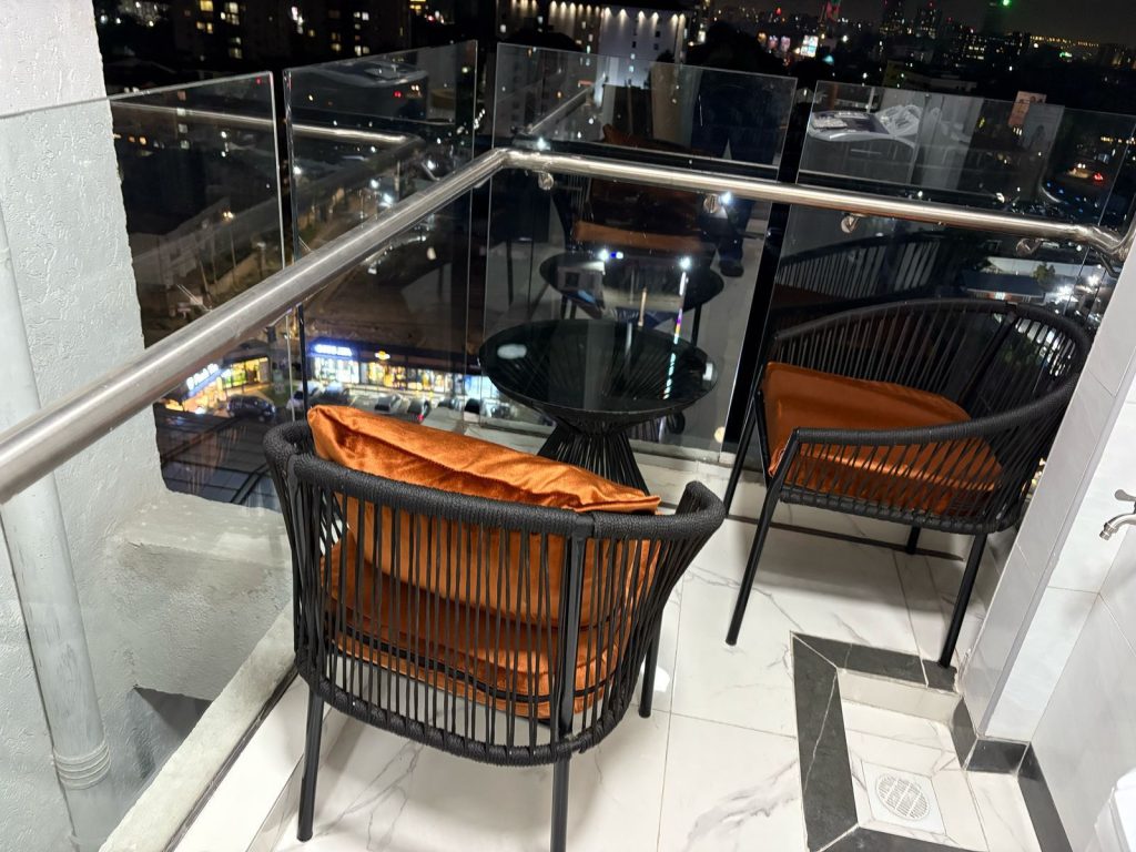 balony with 2 seats and a medium size table at night inside the Short Stay Furnished Apartment in Nairobi