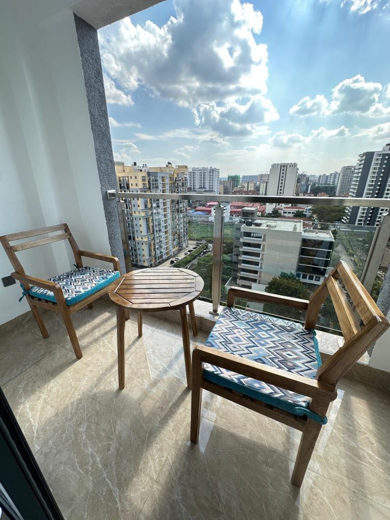 a balcony with 2 seats and a table and nice views at Serviced 1 Bedroom Apartment In Kilimani