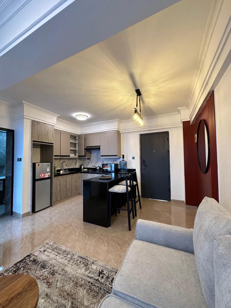 open plan kitchen with a breakfast bar, cabinets and appliances at Serviced 1 Bedroom Apartment In Kilimani