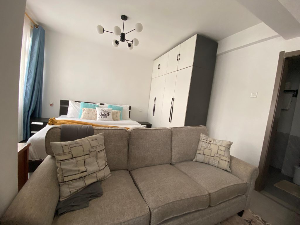 view of the living room area with a couch, a bed and inbuilt wardrobes at Furnished Studio Apartment in Kilimani