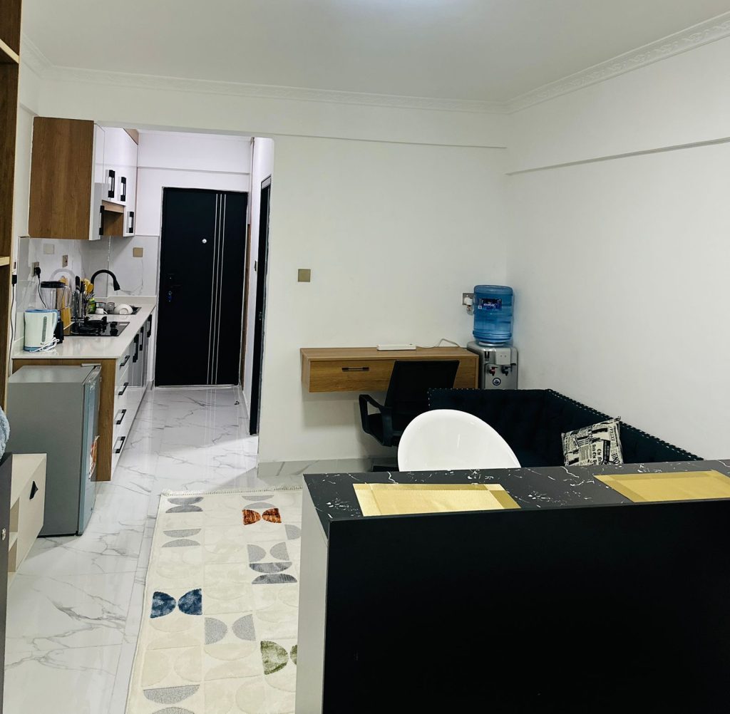 the view of the working desk and a chair nrxt to a water dispencer at Furnished Studio Airbnb in Kilimani Nairobi
