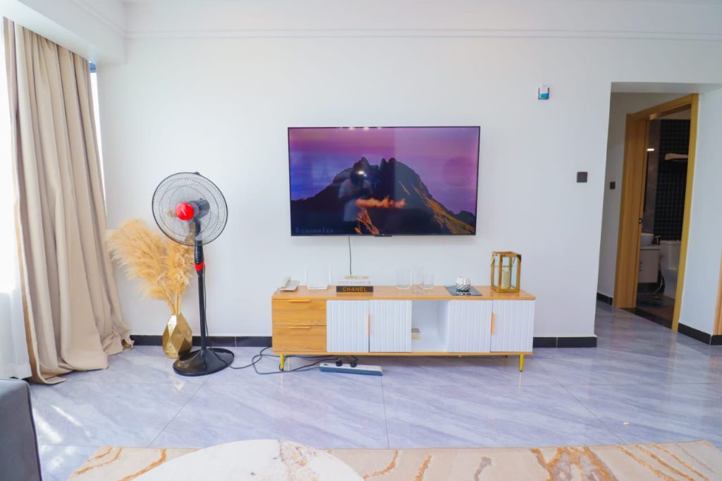 mounted smart tv with a tv console at Furnished 3 Bedroom Airbnb in Kilimani