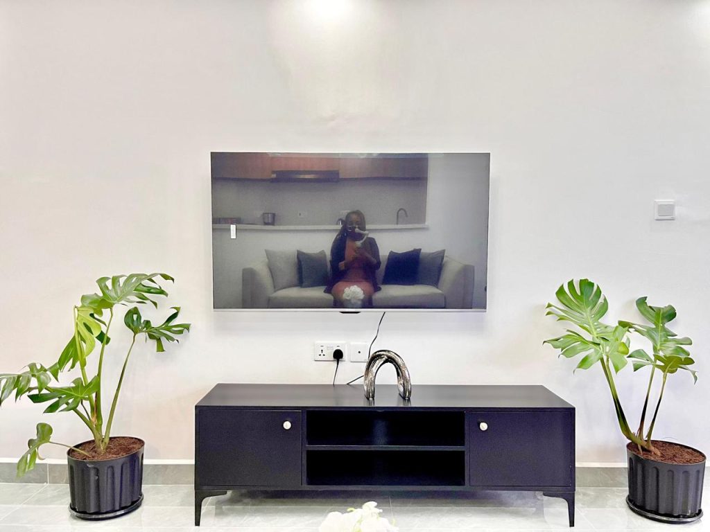Mounted Smart Tv and a Tv console below it at Short-Term Accomodation Furnished Apartment in Westlands