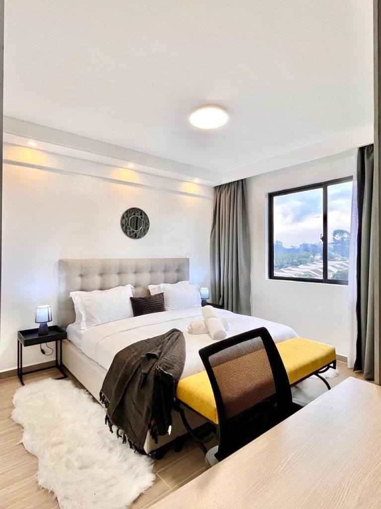 the king size bed and th study desk at a bedroom in the Short-Term Accomodation Furnished Apartment in Westlands
