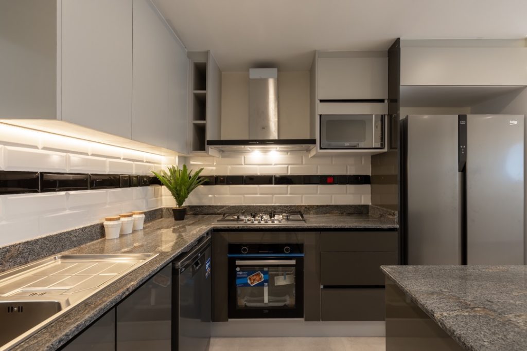 an elegant open plan kitchen with fitted cabinets, a cooker and hood at greenvile apartment