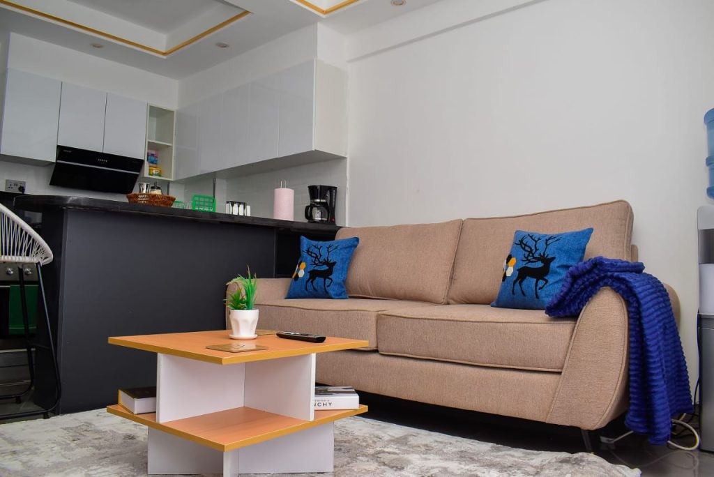 Cozy two-seater couch with a partial view of the modern open plan kitchen in an affordable furnished apartment in Kileleshwa Nairobi.
