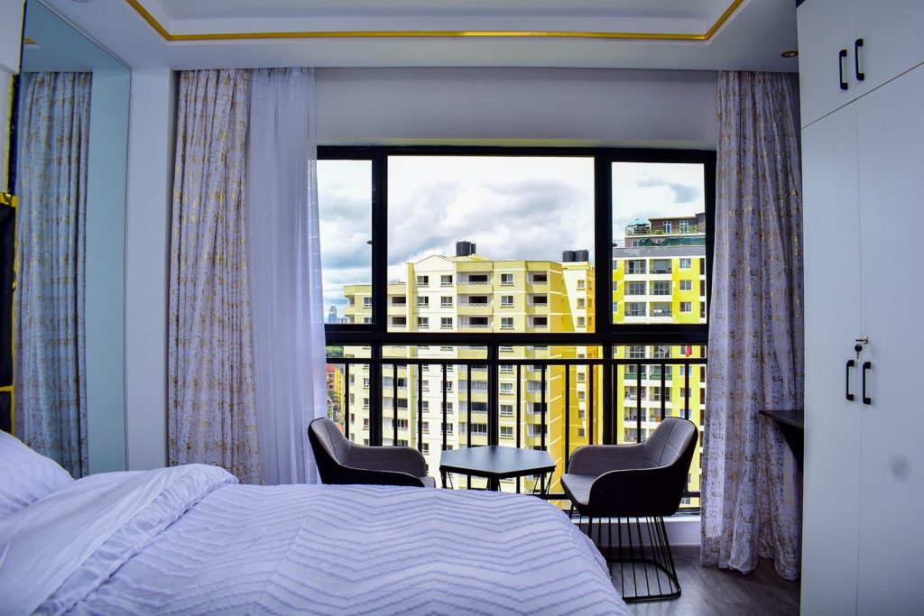 Bedroom with large windows offering scenic views in Airbnb Apartment in Kileleshwa Nairobi.