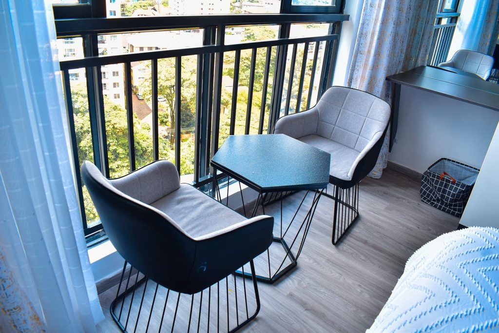 a balcony with 2 seats and a medium table for relaxation at Airbnb apartment in kileleshwa