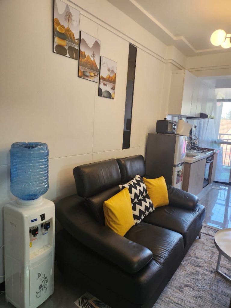 Black 2-seater leather sofa in the lounge of a serviced 2 bedroom apartment in Kilimani Nairobi