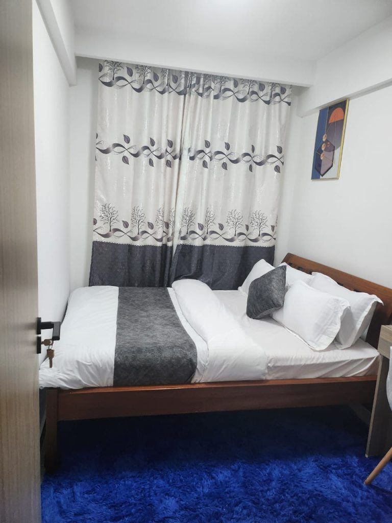 Second bedroom with a queen size bed and fitted wardrobes in a serviced 2 bedroom apartment in Kilimani Nairobi