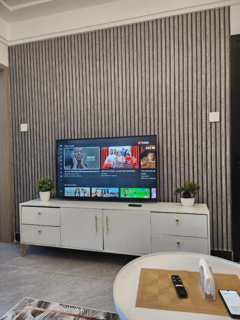 Smart TV on top of a white elongated cabinet in the living room of a serviced 2 bedroom apartment in Kilimani Nairobi