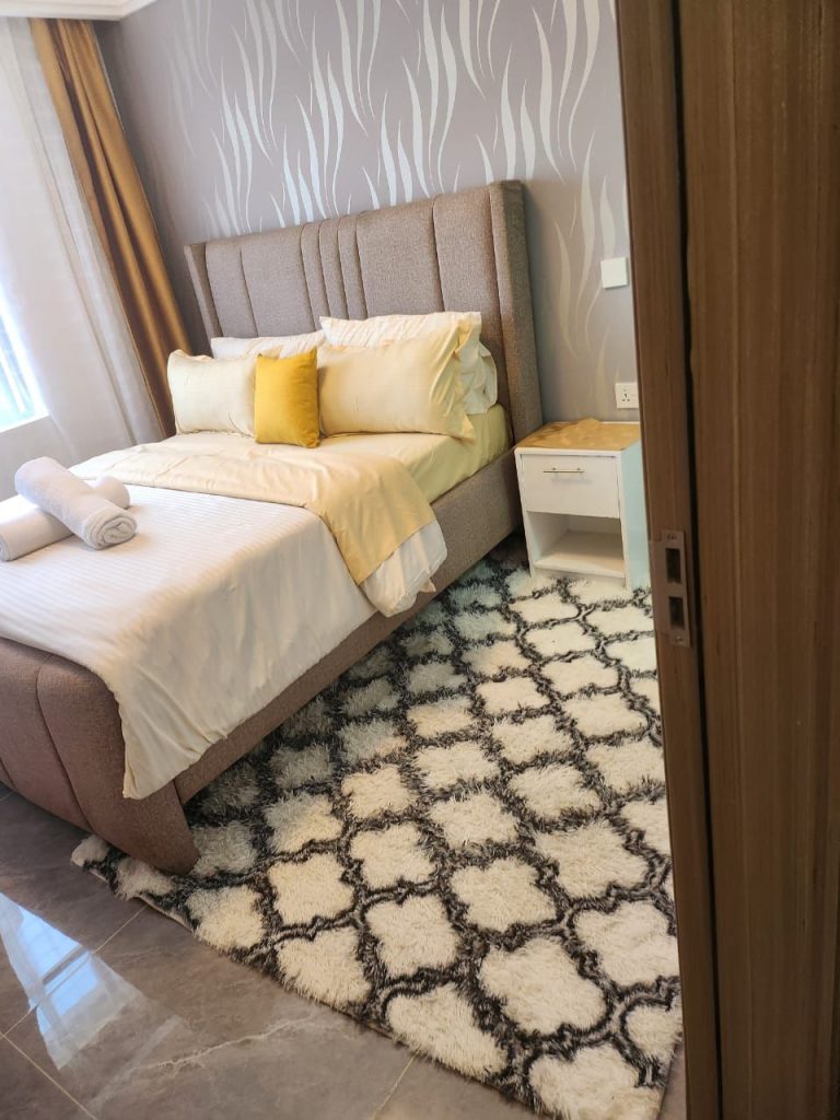 Comfortable queen size bed in a well-lit bedroom of a serviced 2 bedroom apartment in Kilimani Nairobi