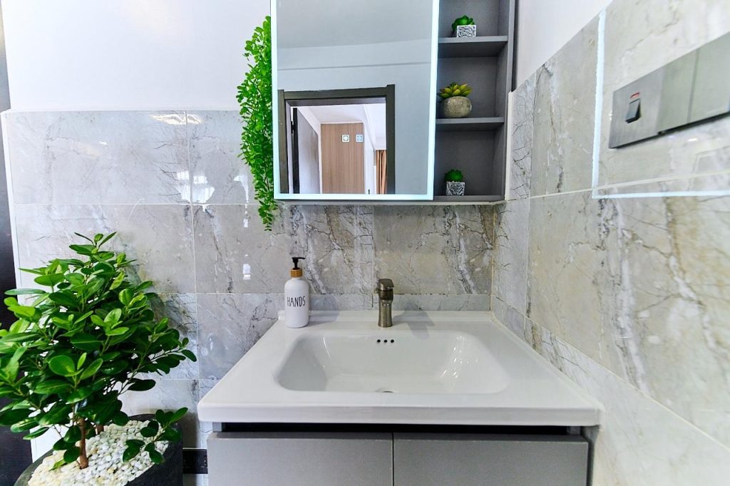 A modern sink and a mirror with storage at the pay per night apartment in lavington