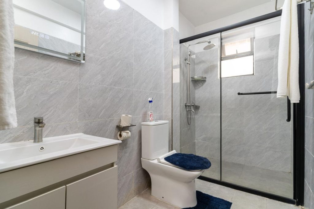 Bathroom with cubicle shower, toilet, and sink in a furnished apartment in Kileleshwa for rent.