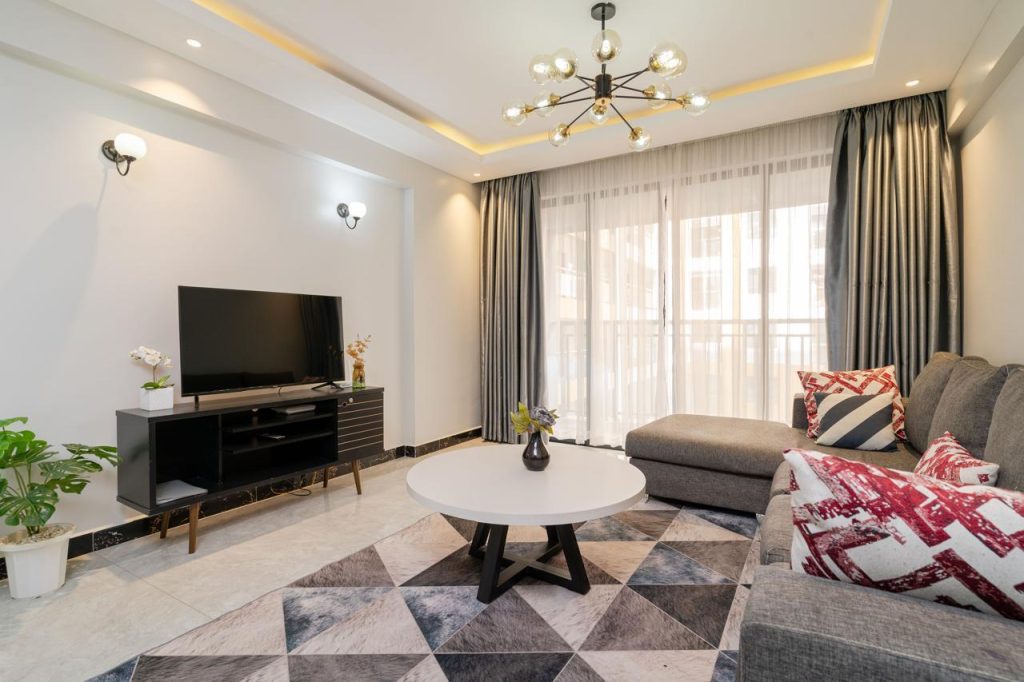 Bright living room with large windows and chandelier in a furnished apartment in Kileleshwa for rent.