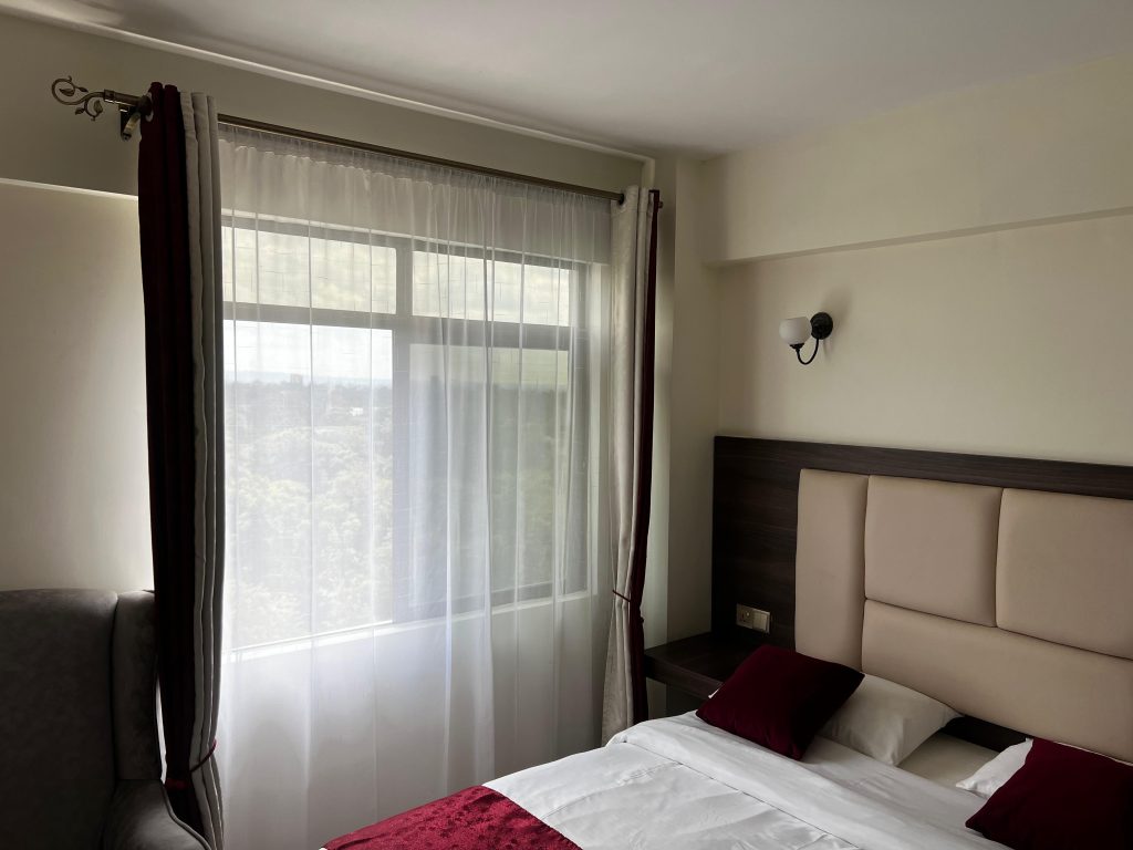 Bright bedroom with large windows and a queen-sized bed in a short stay 2 bedroom apartment in Kileleshwa Nairobi