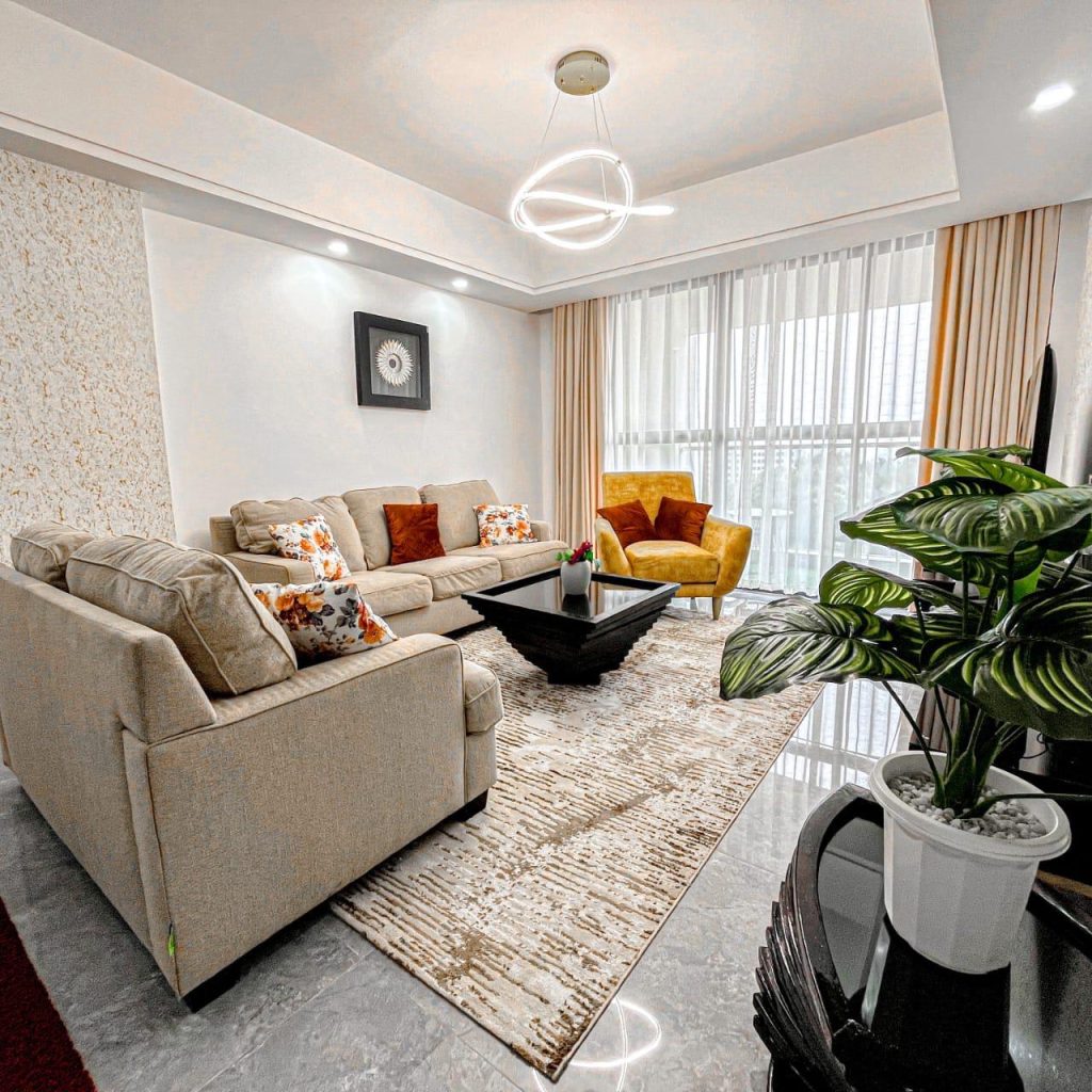 Elegant living room with a 3-seater, 3-seater, and single seat, large windows allowing natural light in – Furnished Apartment for Short Stays in Nairobi.