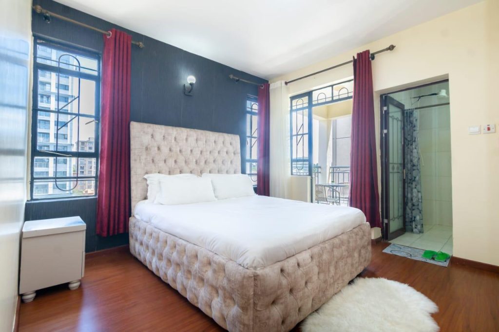 Master bedroom in Mararo Court Furnished Apartment in Lavington with large bed and wardrobe.