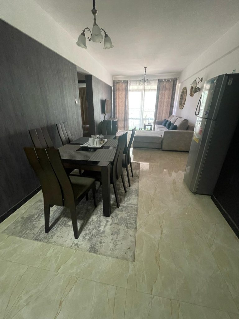 classic dining area set and the living room in the backround well lit with natural lighting from large windows at cheap serviced 2 bedroom apartment in Nairobi
