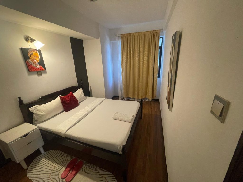 master beedroom with a comfortable bed covered with white beddings at cheap serviced 2 bedroom apartment in Nairobi