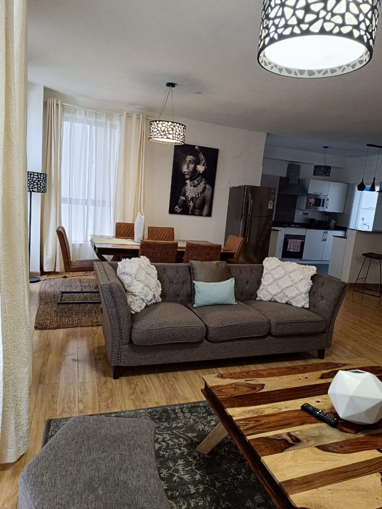 2-seater sofa with a dining set in the background – Serviced 2 Bedroom Duplex Apartment in Nairobi