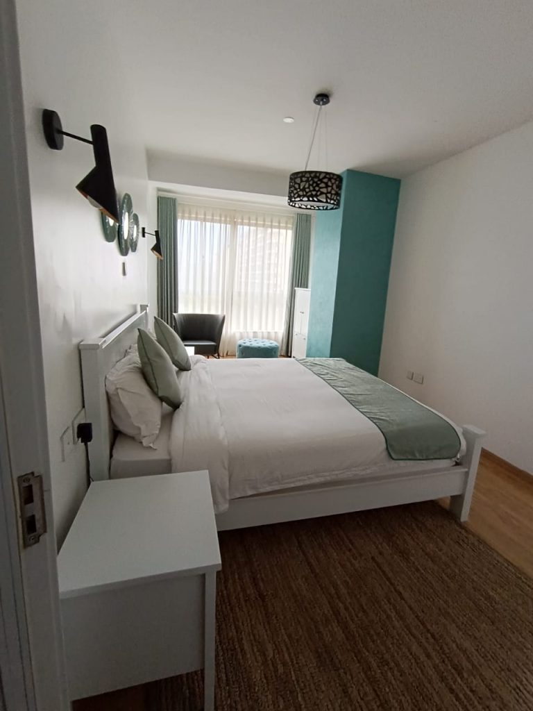 Bright bedroom with queen sized bed and large windows in a furnished duplex apartment for short stay in Kilimani