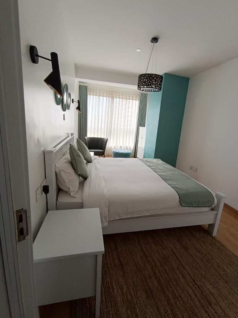 Queen size bed with white beddings in a stylish bedroom of a furnished duplex apartment for short stay in Kilimani